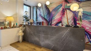 Un área de recepción moderna con una encimera de mármol, un mural abstracto de colores y un piso de madera.