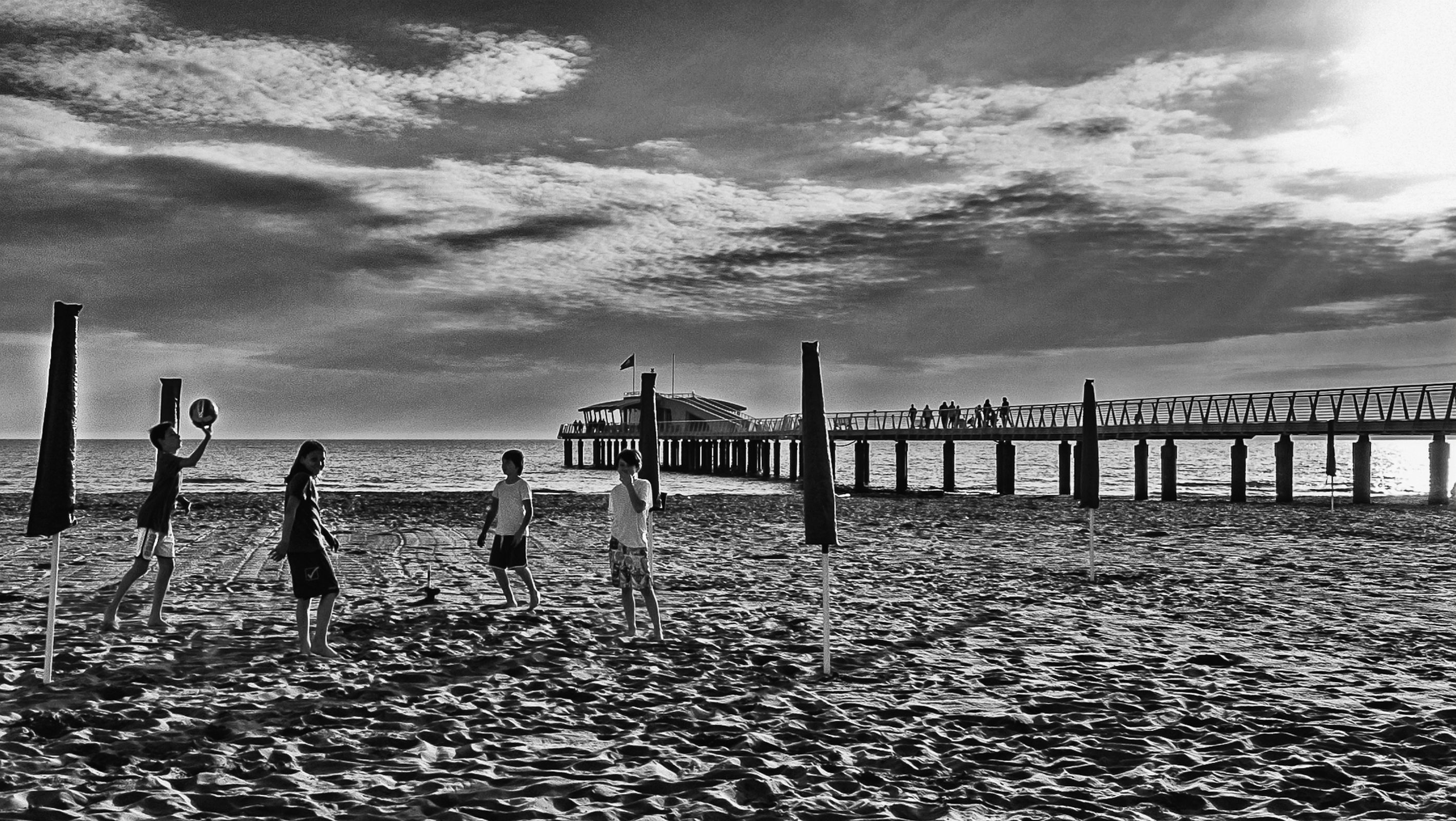 Een steiger die zich uitstrekt over de zee, met een strand op de voorgrond.