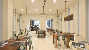 Un comedor amplio con varias mesas y sillas, suelo de mármol e iluminación colgante de cuerda.