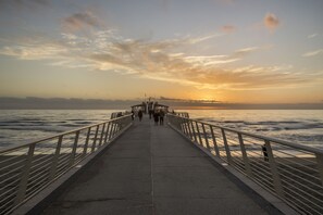 Une jetée s’avançant dans des eaux calmes, avec un coucher de soleil en arrière-plan.