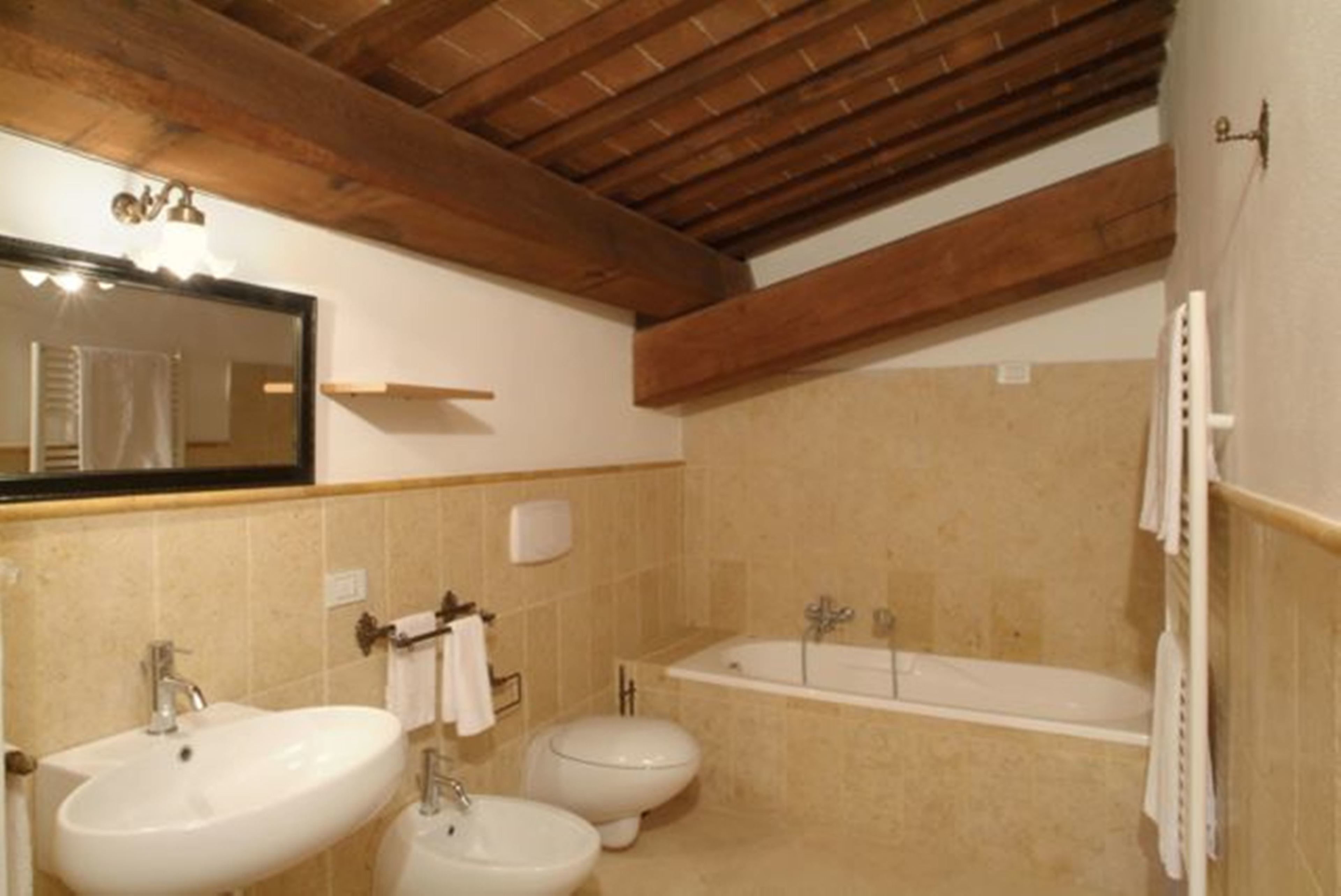 A bathroom with a wooden ceiling, a large sink, a bidet, and a bathtub.