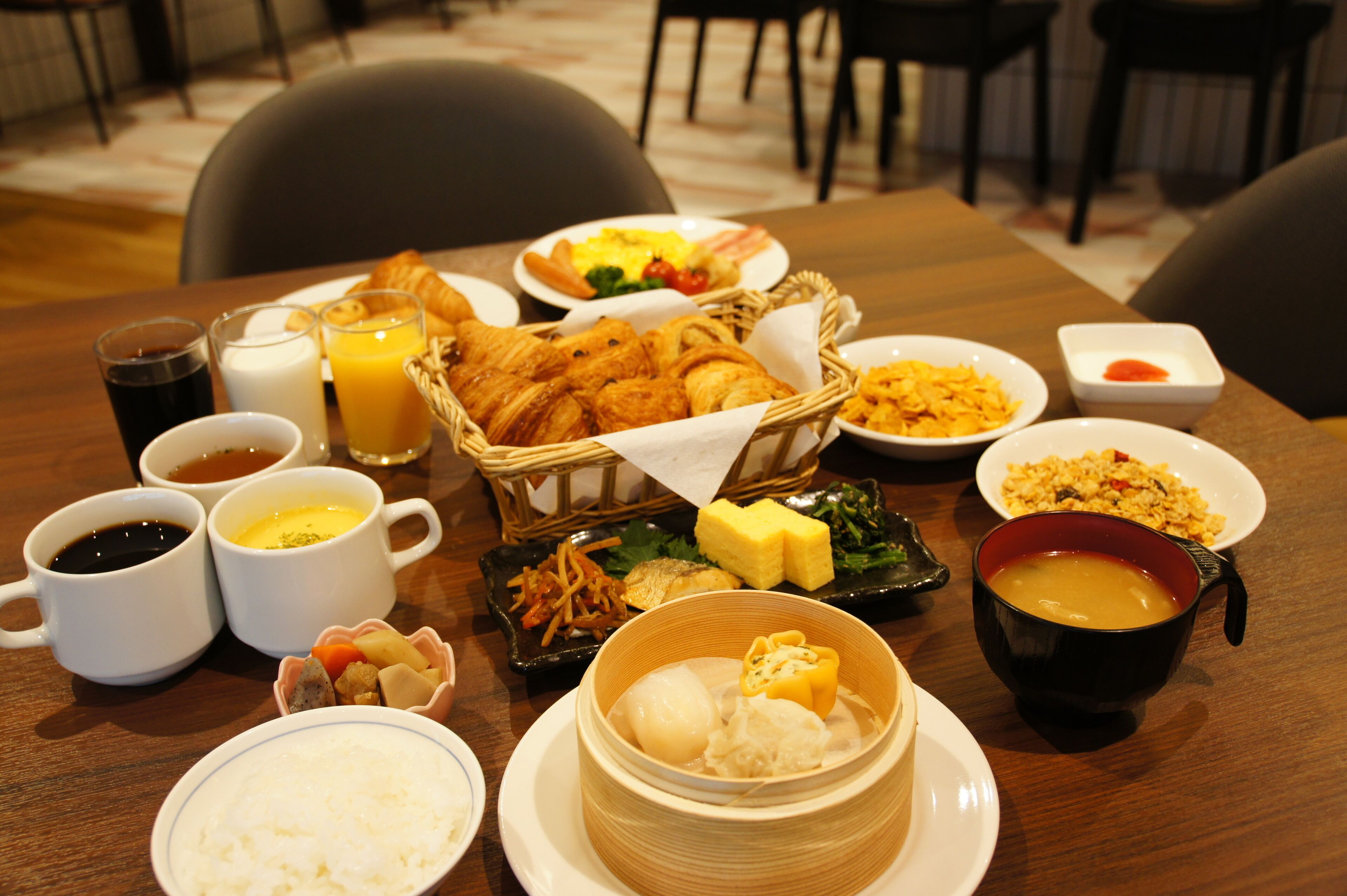 A breakfast table with various dishes including croissants, eggs, and a bowl of soup.