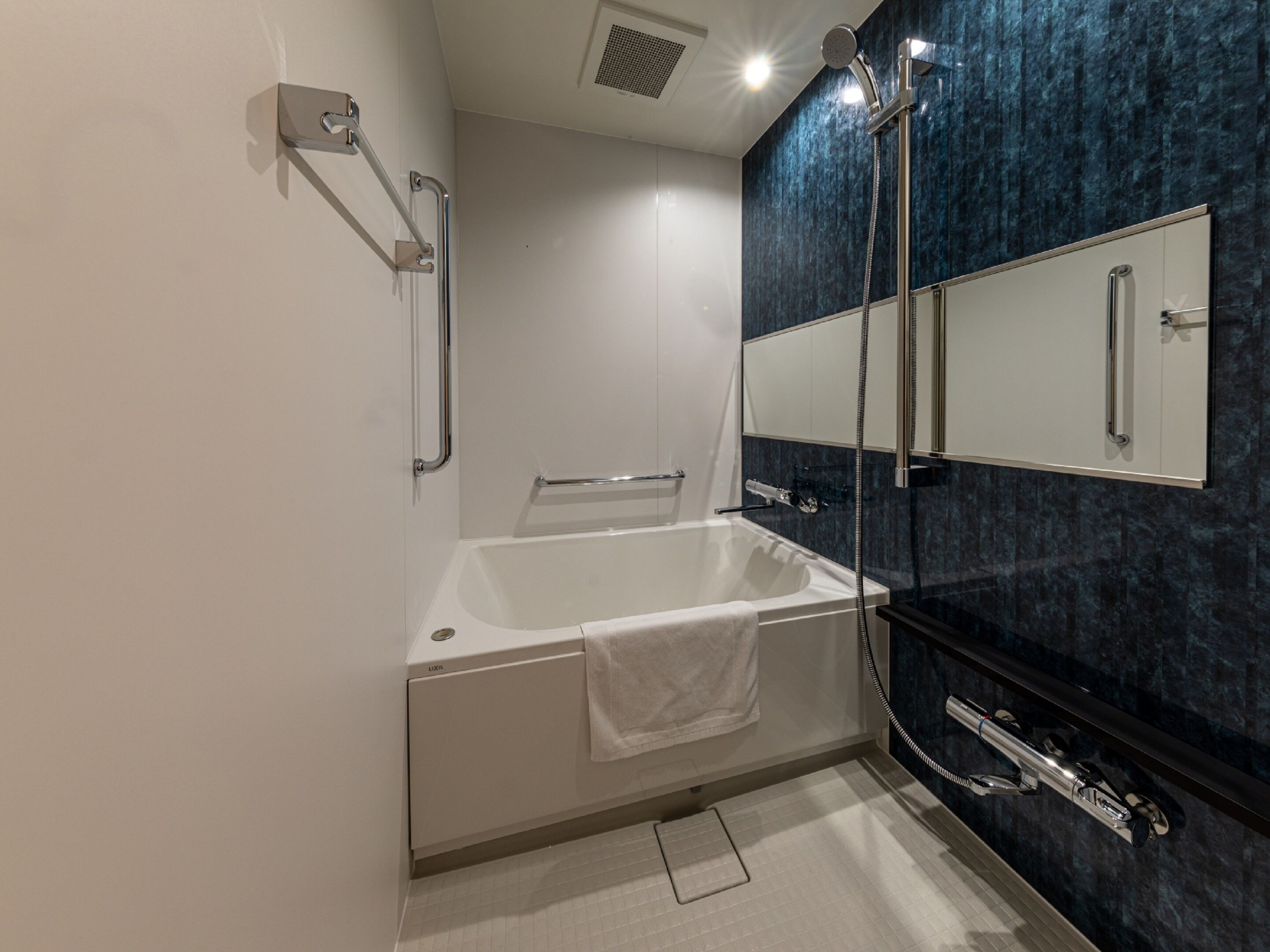 Un baño moderno con bañera, ducha y un espejo grande.