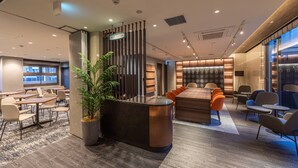 Un espacio lounge moderno con mostrador de recepción, asientos y un amplio ventanal.