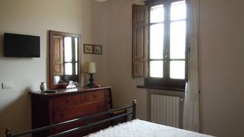 Quarto com cama, cômoda, espelho e janela com cortinas.