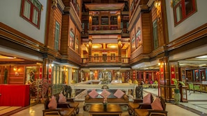 Un interior tradicional con una piscina central, muebles ornamentados y una zona de estar en rojo.