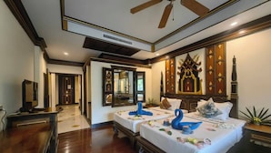 Habitación de hotel con dos camas, ventilador de techo y decoración tradicional.