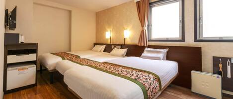 Habitación de hotel con dos camas, un escritorio, un minibar y una ventana con cortinas.