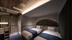 A modern hotel room with two beds, a built-in desk, and a unique curved headboard. - Dotonbori Hotel (Osaka)