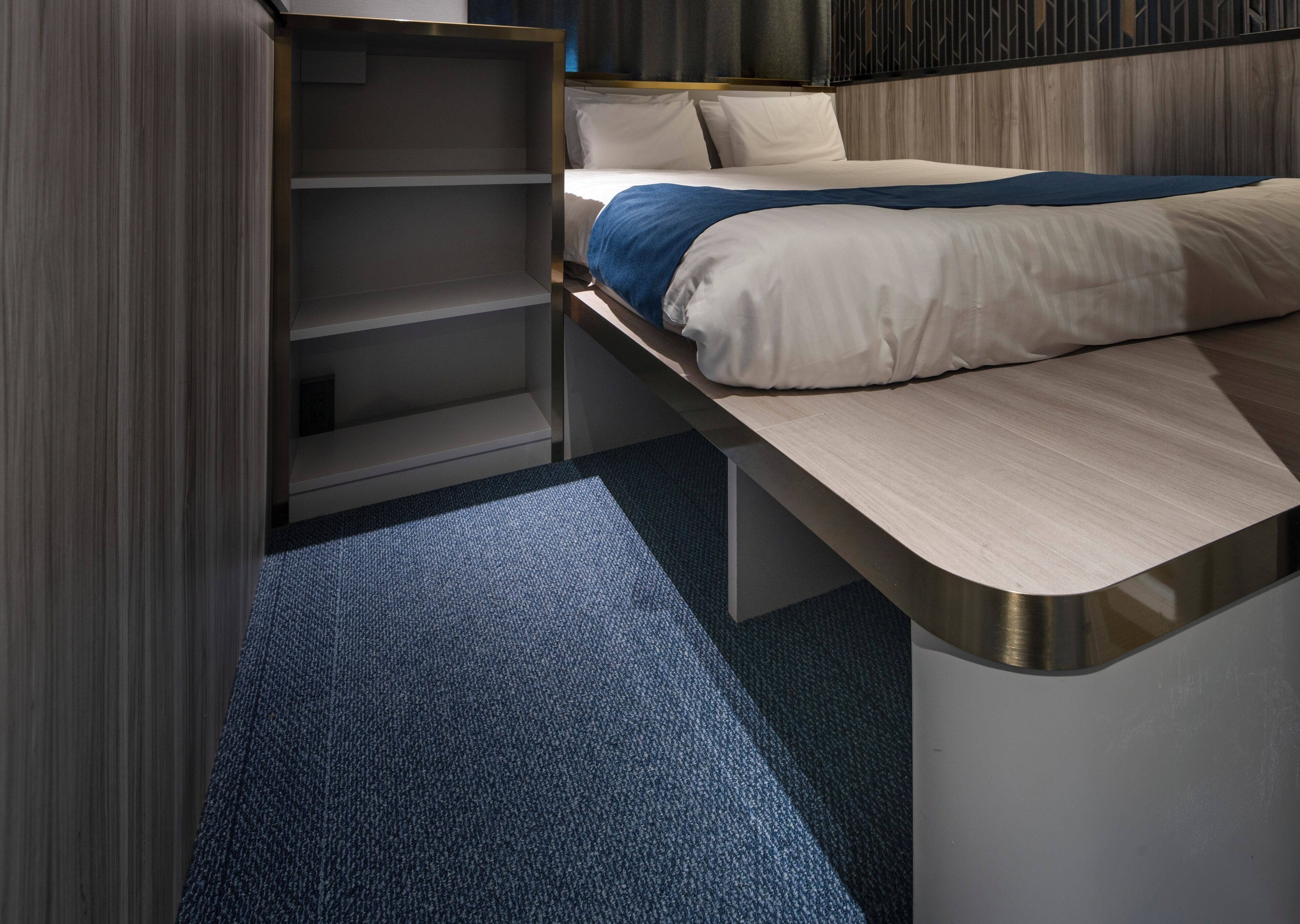 Une chambre d’hôtel moderne équipée d’un lit, d’une banquette intégrée et d’une armoire.