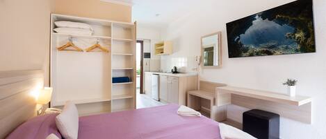 Una habitación de hotel moderna con cama, armario, escritorio y baño.