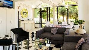 A living room with a checkered floor, a grey sofa, a black armchair, and a glass coffee table. - Terinikos Sunny Garden Hotel & Junior Suites (Rhodes)