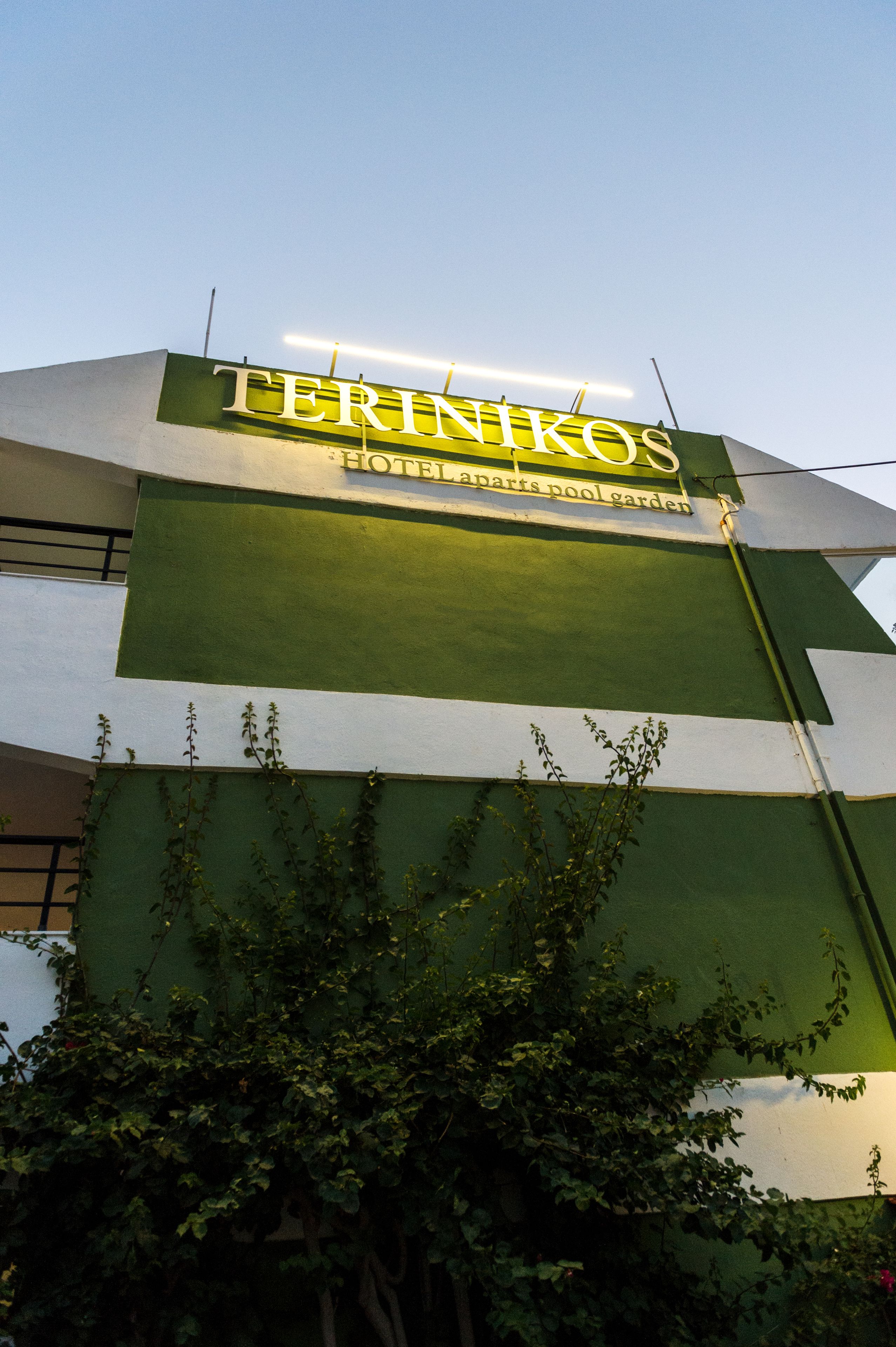 Un edificio con un cartel que dice "TERINKOS HOTEL, APARTS, POOL GARDEN".
