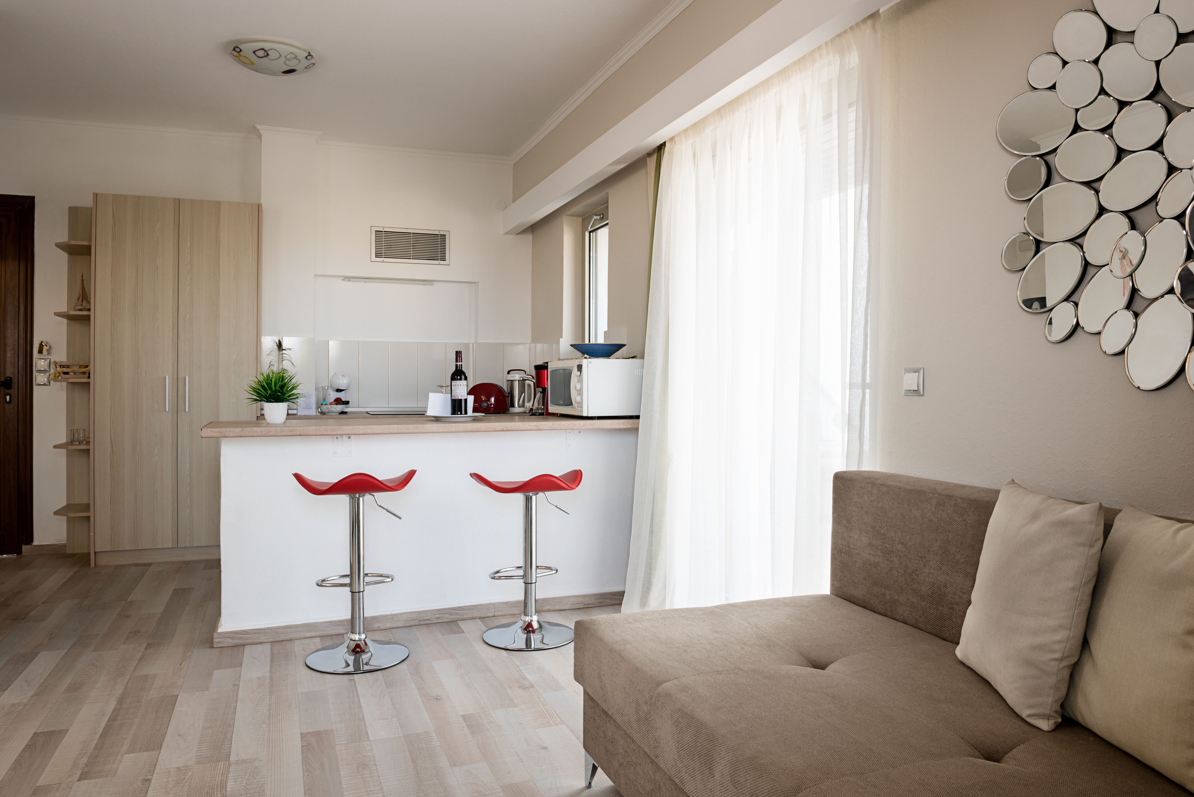 Une cuisine moderne dotée d’un îlot central, de deux tabourets de bar, d’un canapé et d’un miroir fixé au mur.