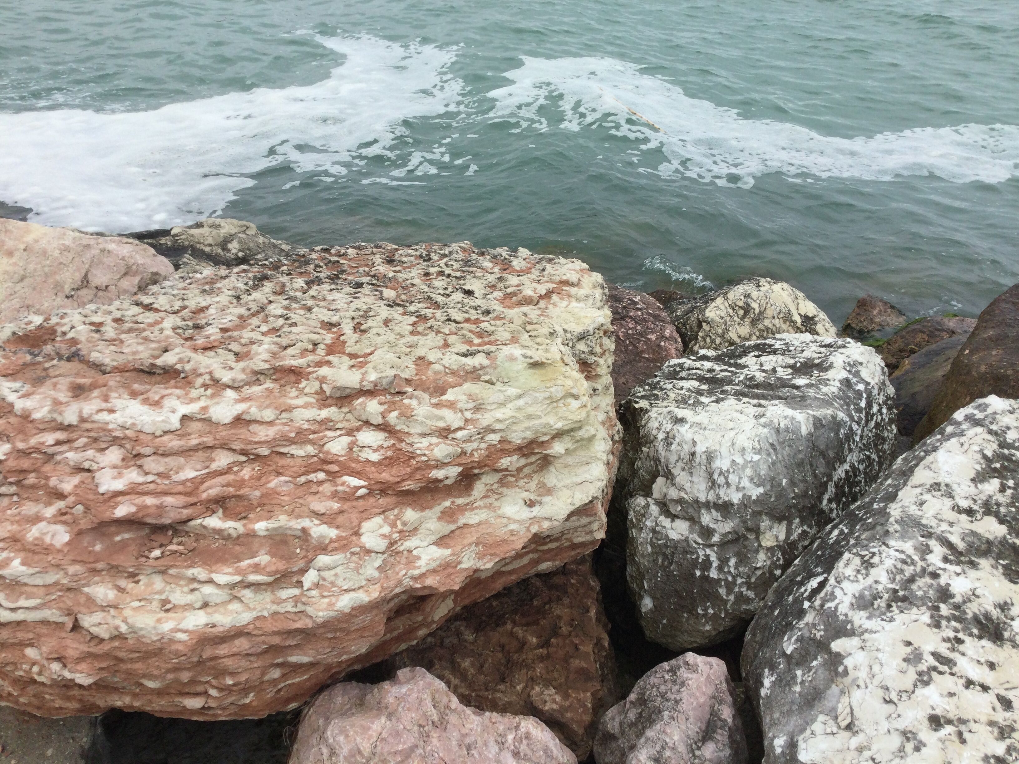 A rocky shoreline with large boulders and waves crashing against them.