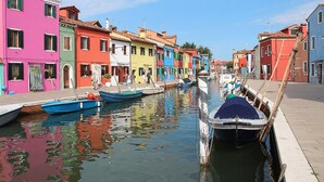 Un canal bordeado de edificios coloridos, con barcos amarrados a lo largo del agua y un cielo despejado.