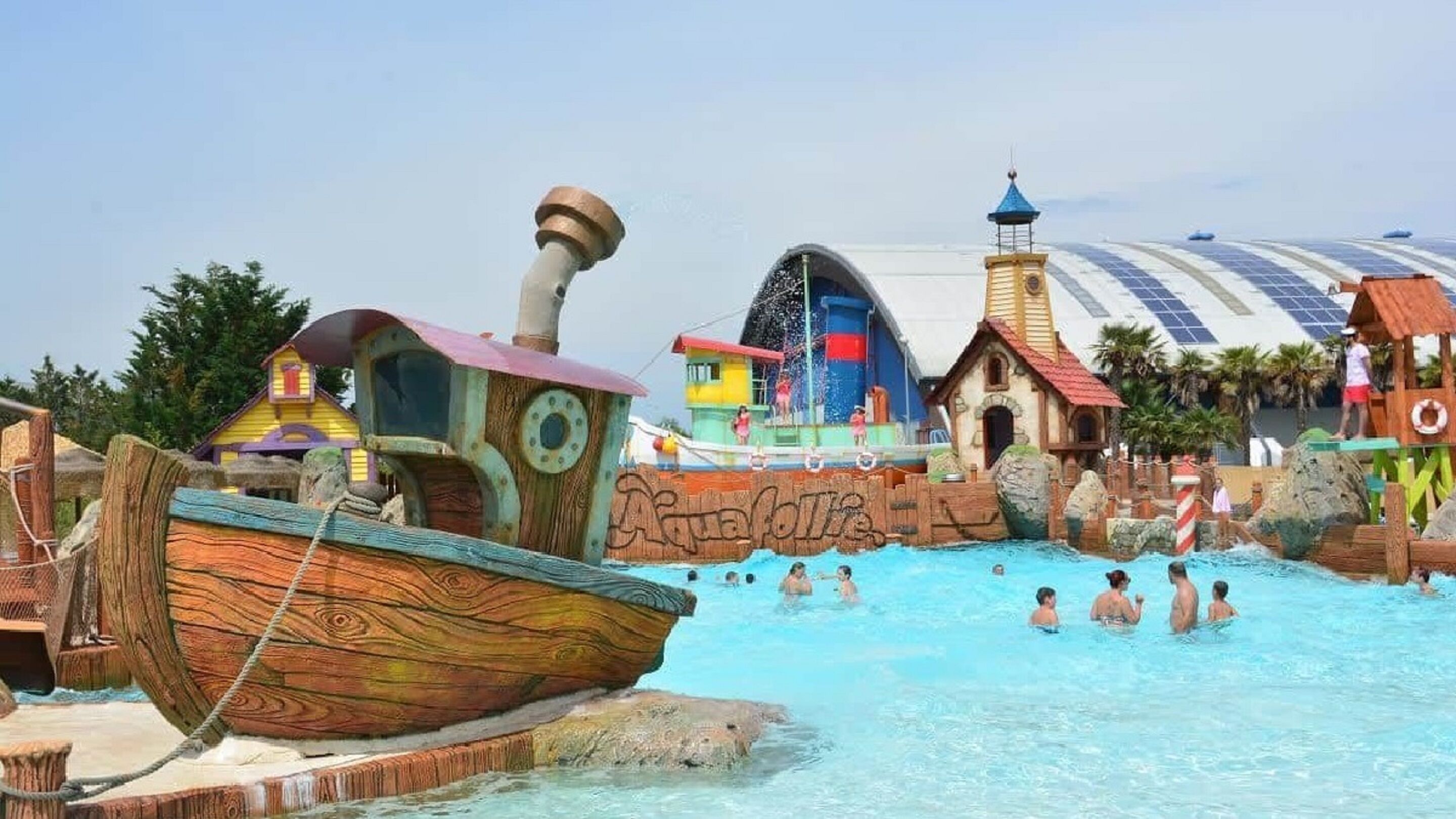 A water park with a wooden boat structure, colorful playhouses, and a large dome-shaped building.