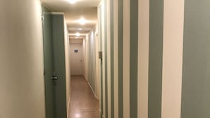 A narrow hallway with striped walls and wooden flooring, leading to a door at the end. - B&B di Piazza del Duomo (Florence)