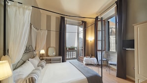 A hotel room with a large bed, a balcony with a table and chairs, a TV, and a view of a building outside. - B&B di Piazza del Duomo (Florence)