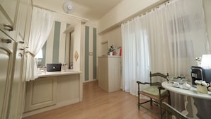 A kitchen with a laptop, a coffee maker, and a dining area with a chair and table. - B&B di Piazza del Duomo (Florence)