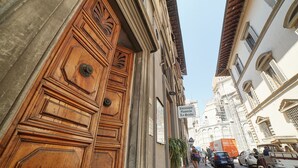 A narrow street with historic buildings, a wooden door with carvings, and a sign for a restaurant. - B&B di Piazza del Duomo (Florence)