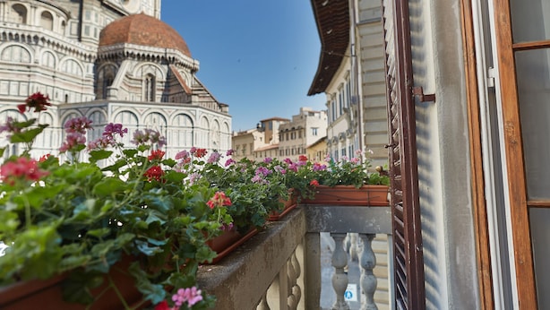 A balcony with potted flowers and a view of a historic building with a dome. - B&B di Piazza del Duomo (Florence)