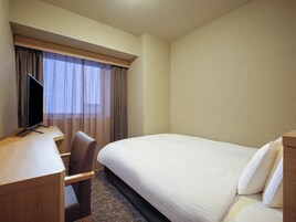 Una habitación de hotel con una cama, un escritorio con televisor y una silla.