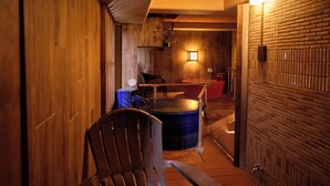 Un interior de madera con un área de estar, un barril azul grande y una bañera roja.
