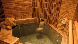 Un jacuzzi con una fuente de agua, un indicador de presión y una escultura de piedra.