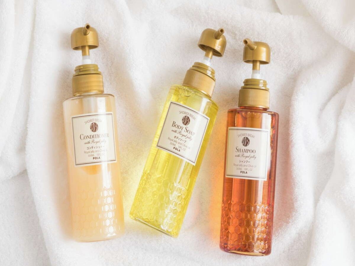 Three bottles of body soap on a white fabric surface.
