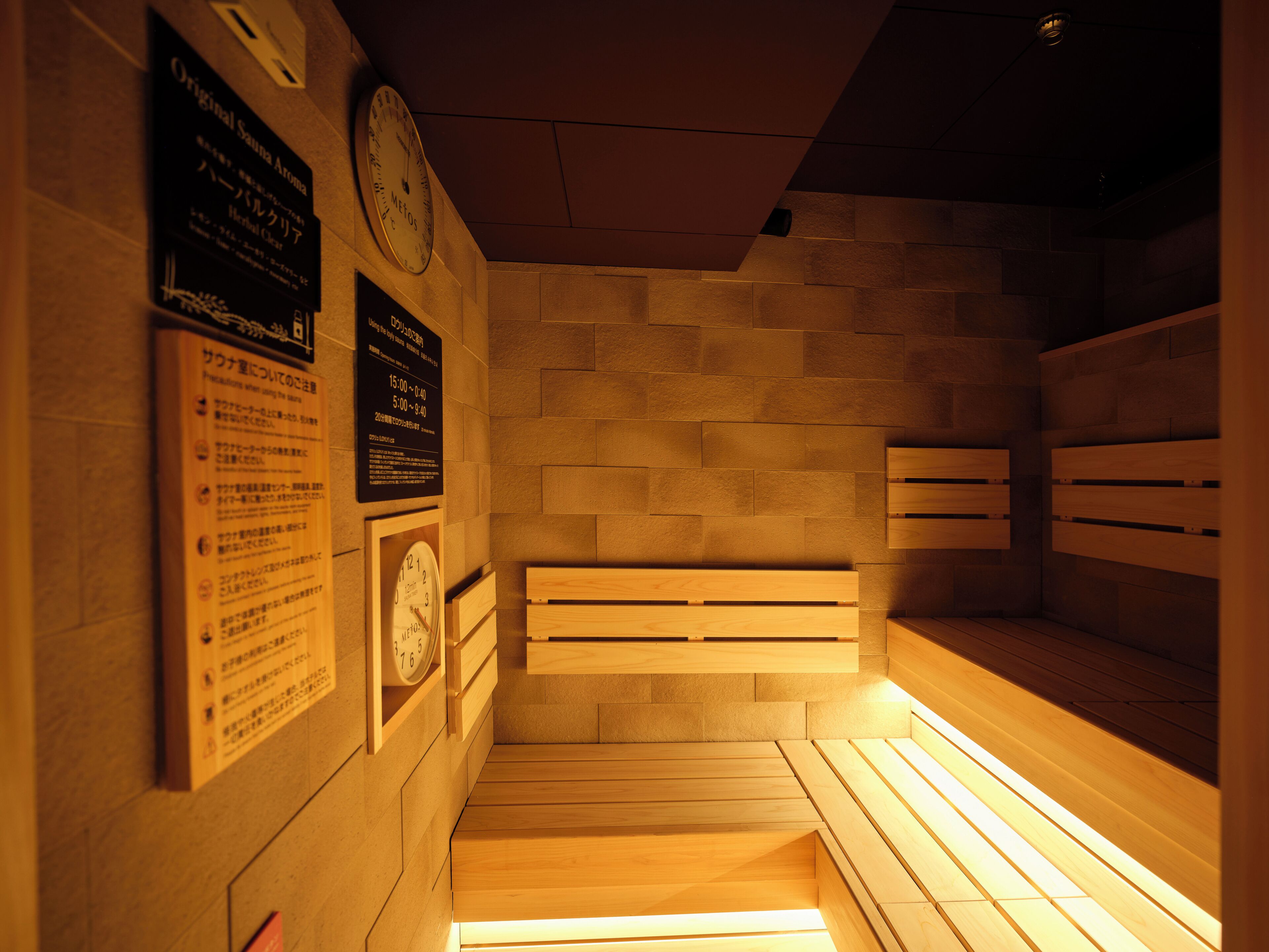 A sauna with wooden benches, a clock, and informational signs on the wall.
