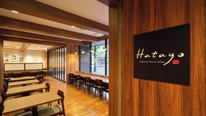 Interior de restaurante con suelos, mesas y sillas de madera. Un cartel en la pared dice 'Hotago Relaxing Time & Coffee'.