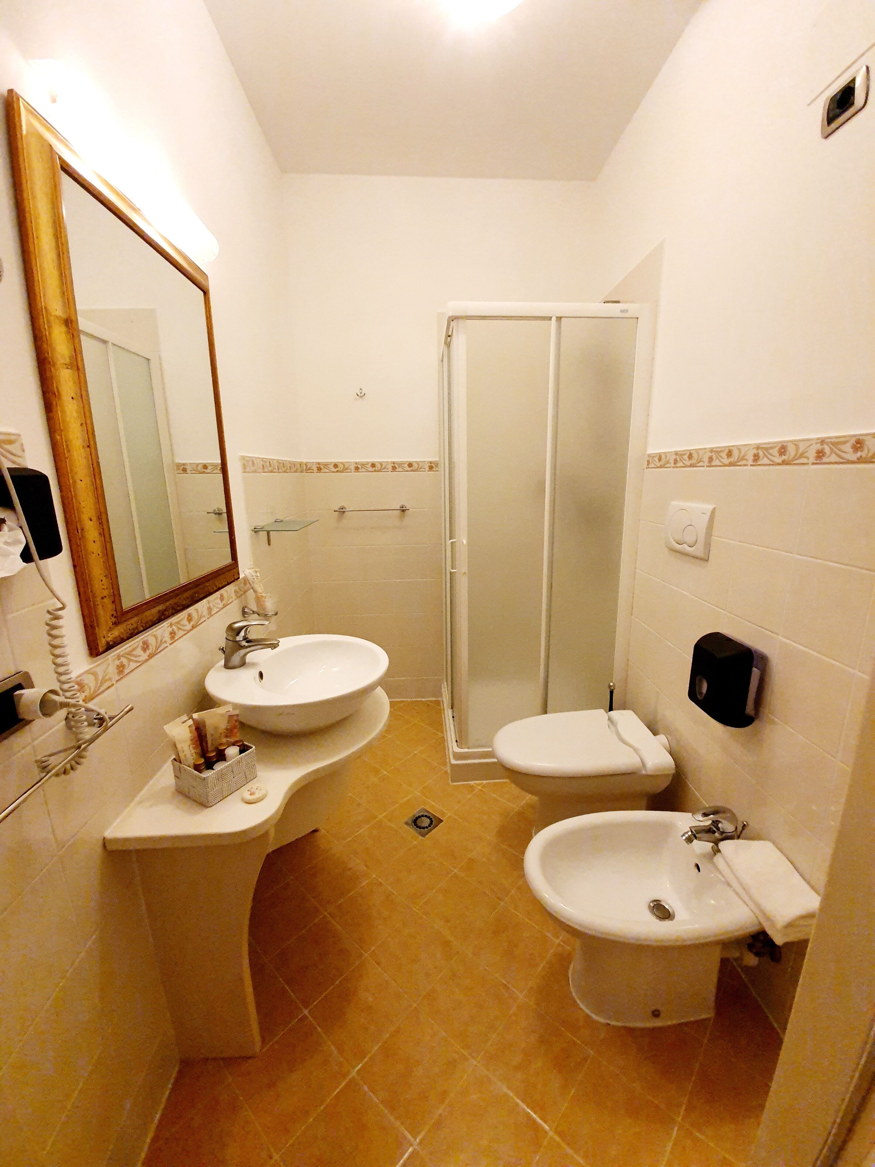 A bathroom with two sinks, a toilet, and a shower.