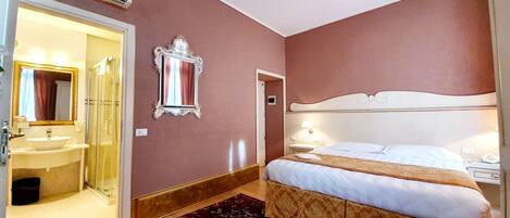 A hotel room with a bed, a bathroom with a sink and mirror, and a patterned rug.