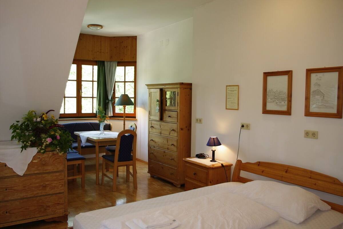 Un dormitorio con cama, cómoda de madera, escritorio con silla y ventana con cortinas.