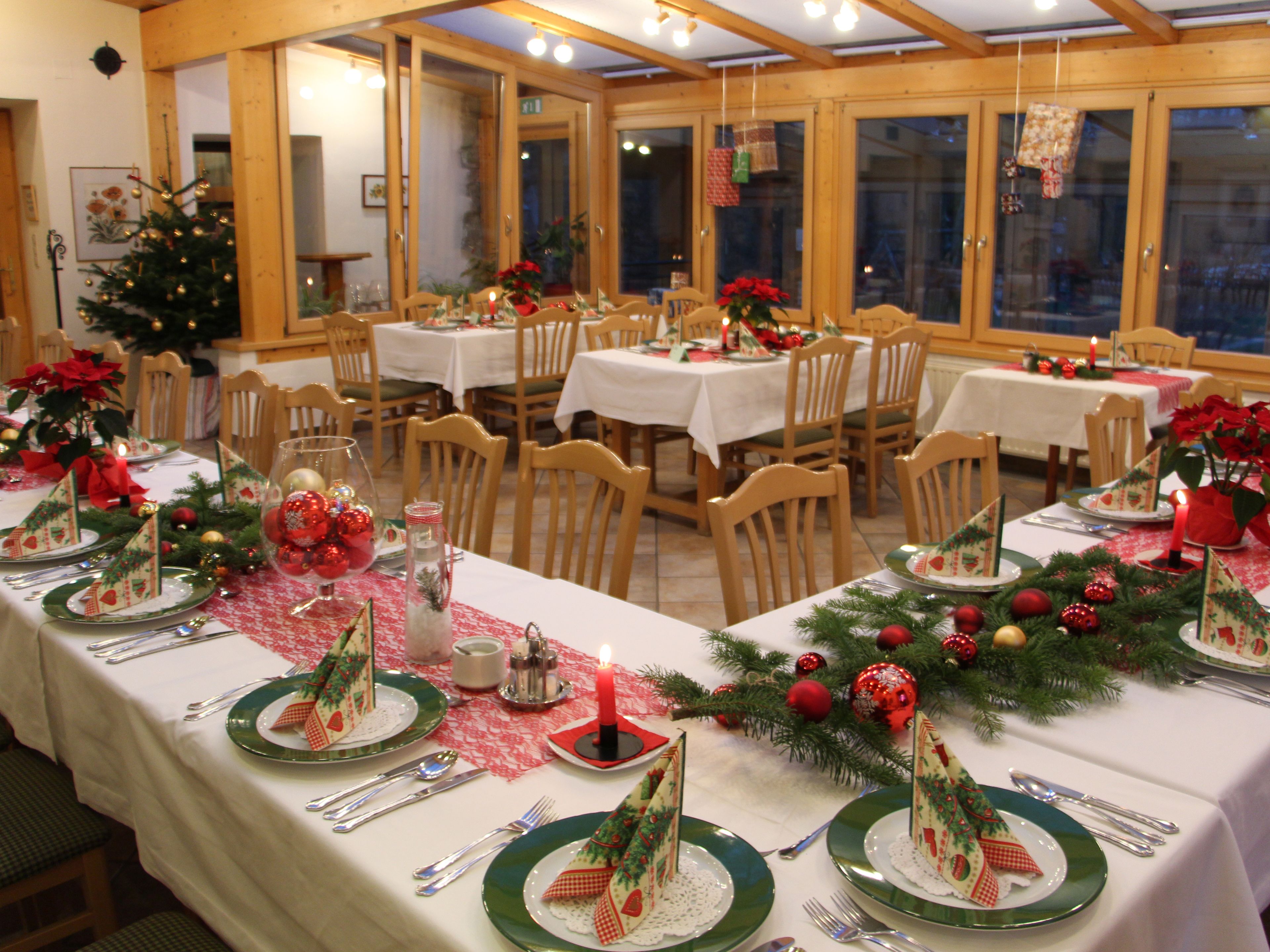 Comedor con mesas dispuestas para una comida, con decoración navideña.