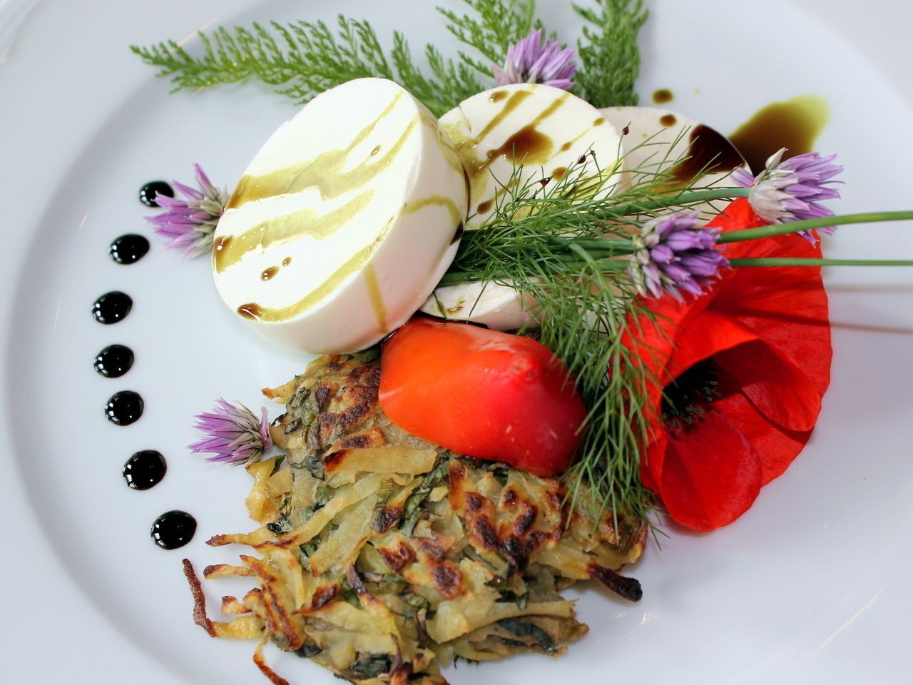 A plate with a potato dish, a boiled egg, a red poppy flower, and some greens.