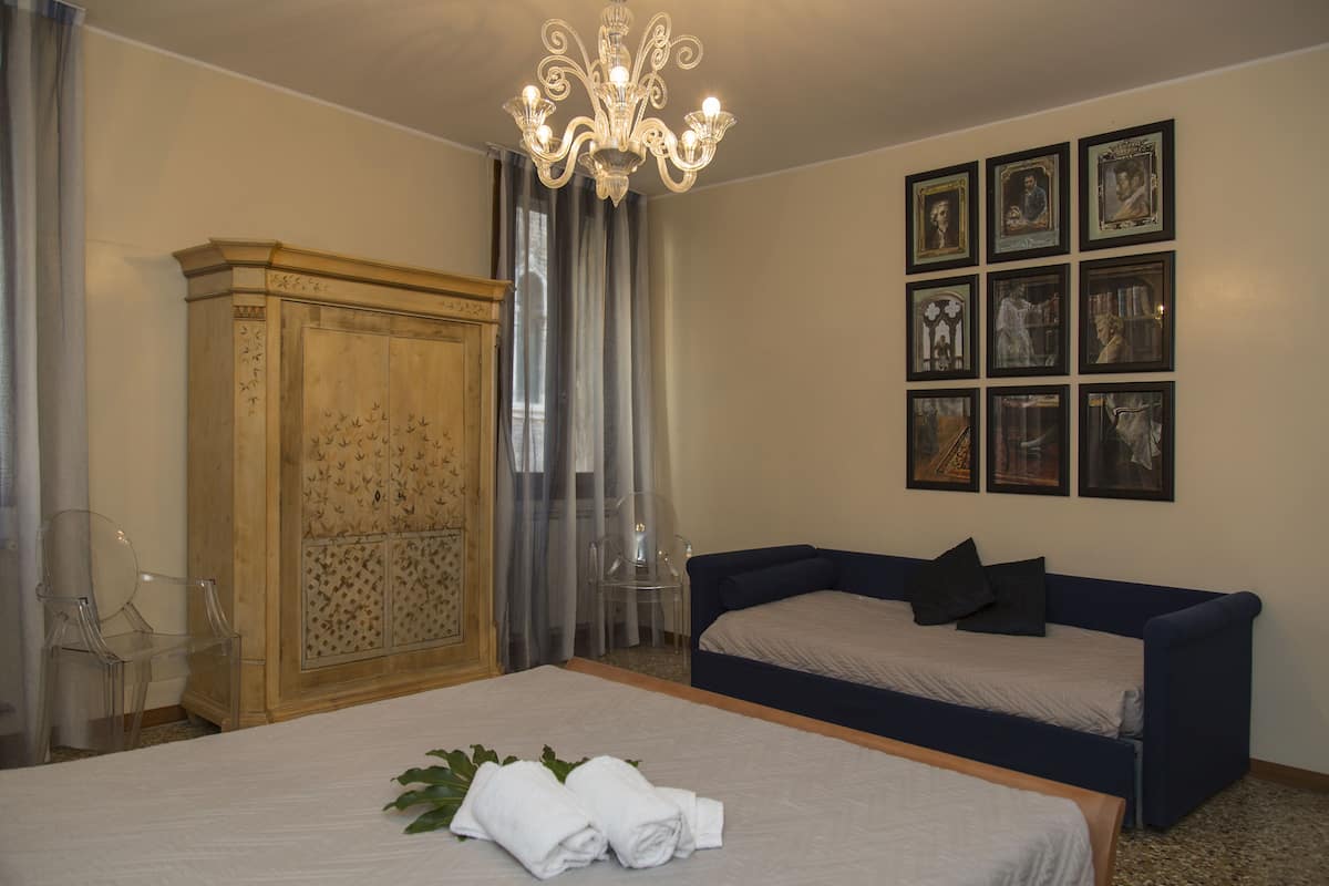 Ein Hotelzimmer mit einem großen Bett, einem blauen Sofa, einem Holzschrank und einer Deckenleuchte.