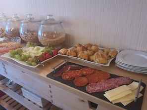 Buffet amb diversos plats, incloent fruita, pastissos i carns.