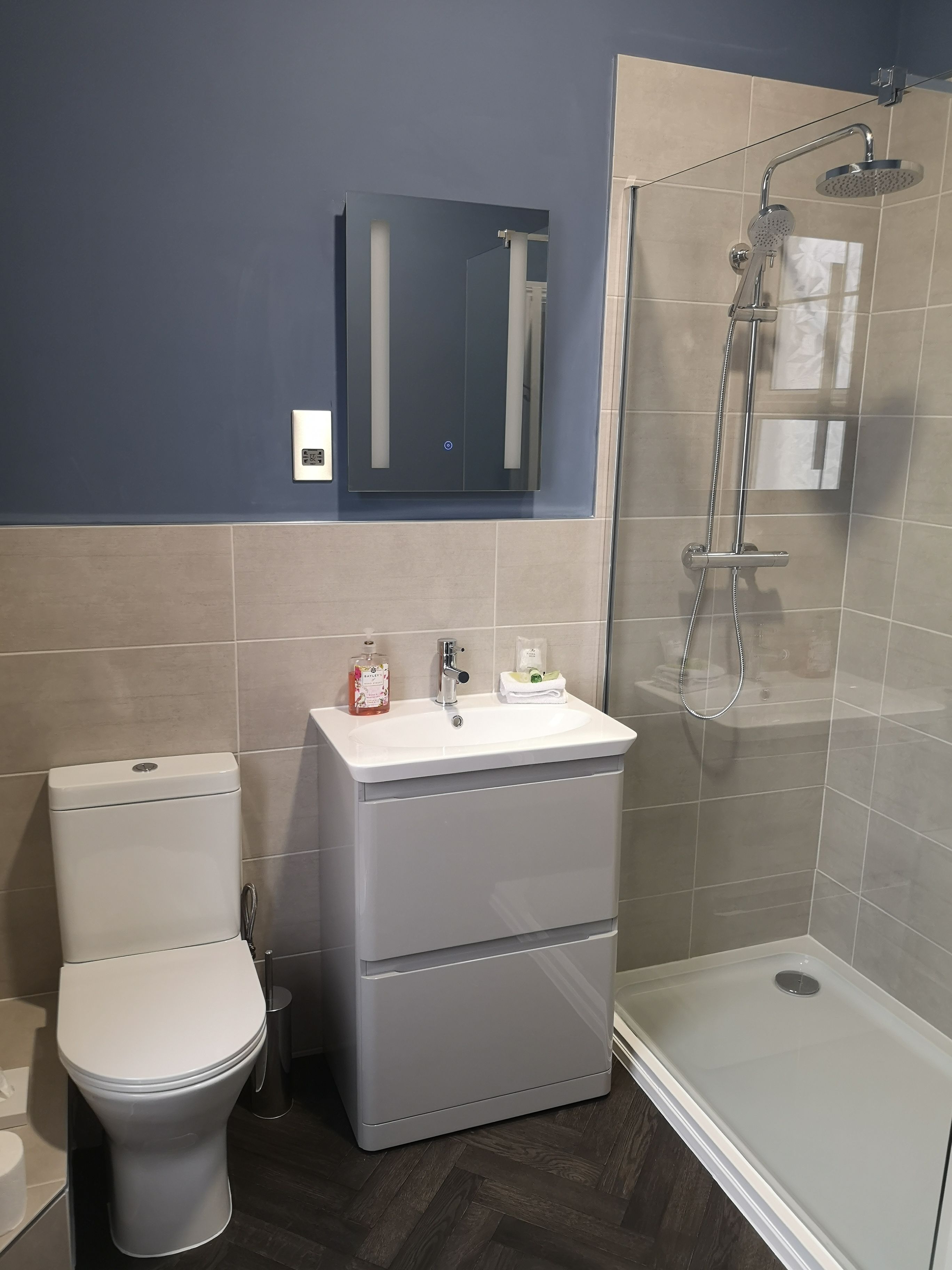 A bathroom with a toilet, a sink, a mirror, and a shower.