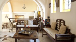 A spacious living room with a high arched ceiling, a wooden coffee table, a sofa, and a dining area with chairs and a table. - Boutique Elizabeth Hotel (Athens)