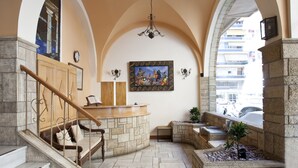 A lobby with a stone reception desk, a staircase with a wooden railing, a chandelier, and a painting on the wall. - Boutique Elizabeth Hotel (Athens)