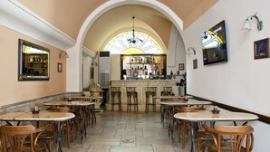 A restaurant with multiple tables and chairs, a bar area, and a large arched window. - Boutique Elizabeth Hotel (Athens)