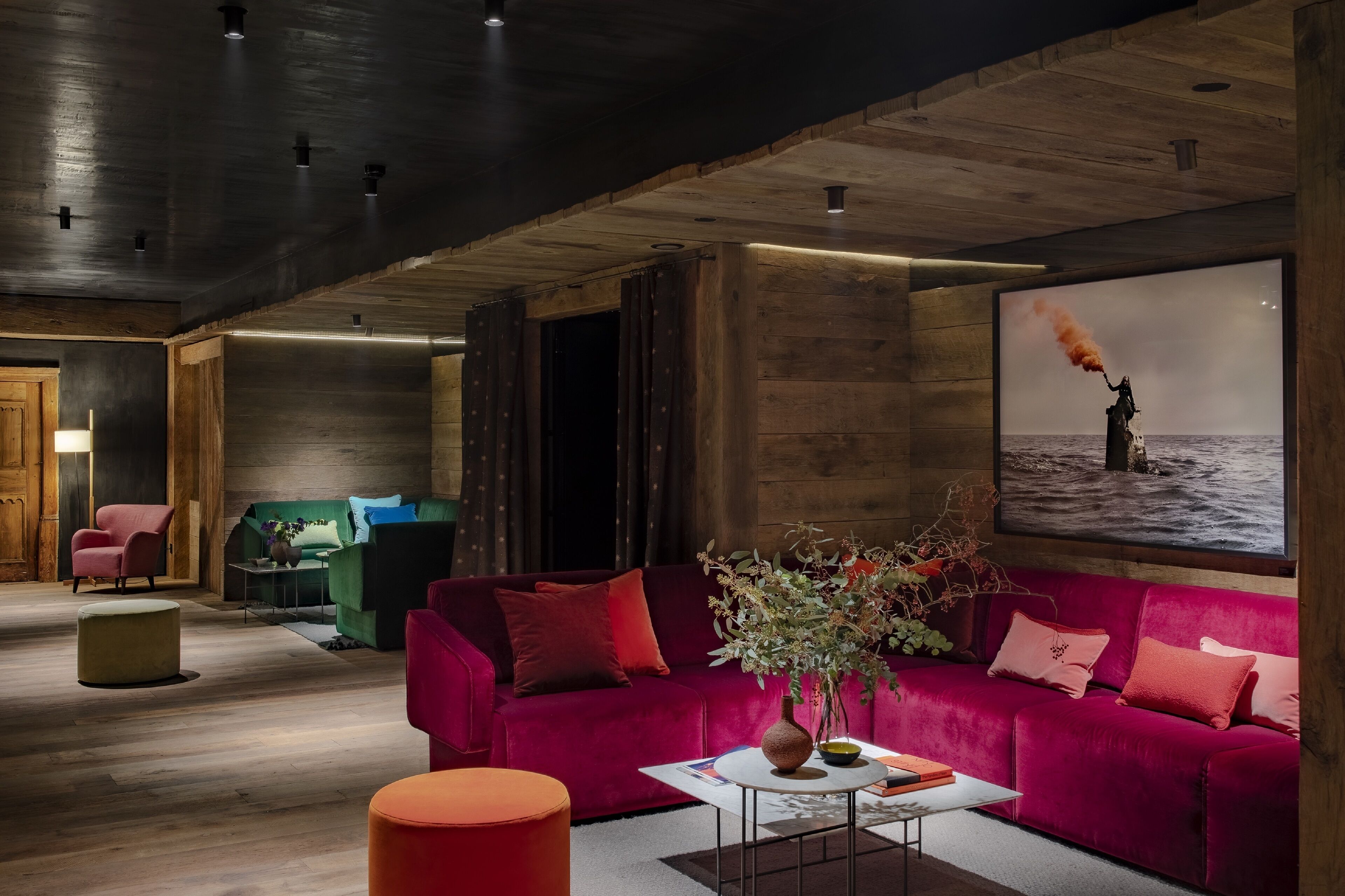 Ein modernes Wohnzimmer mit einem roten Sofa, einem grünen Sessel und einem Couchtisch mit einer Vase.