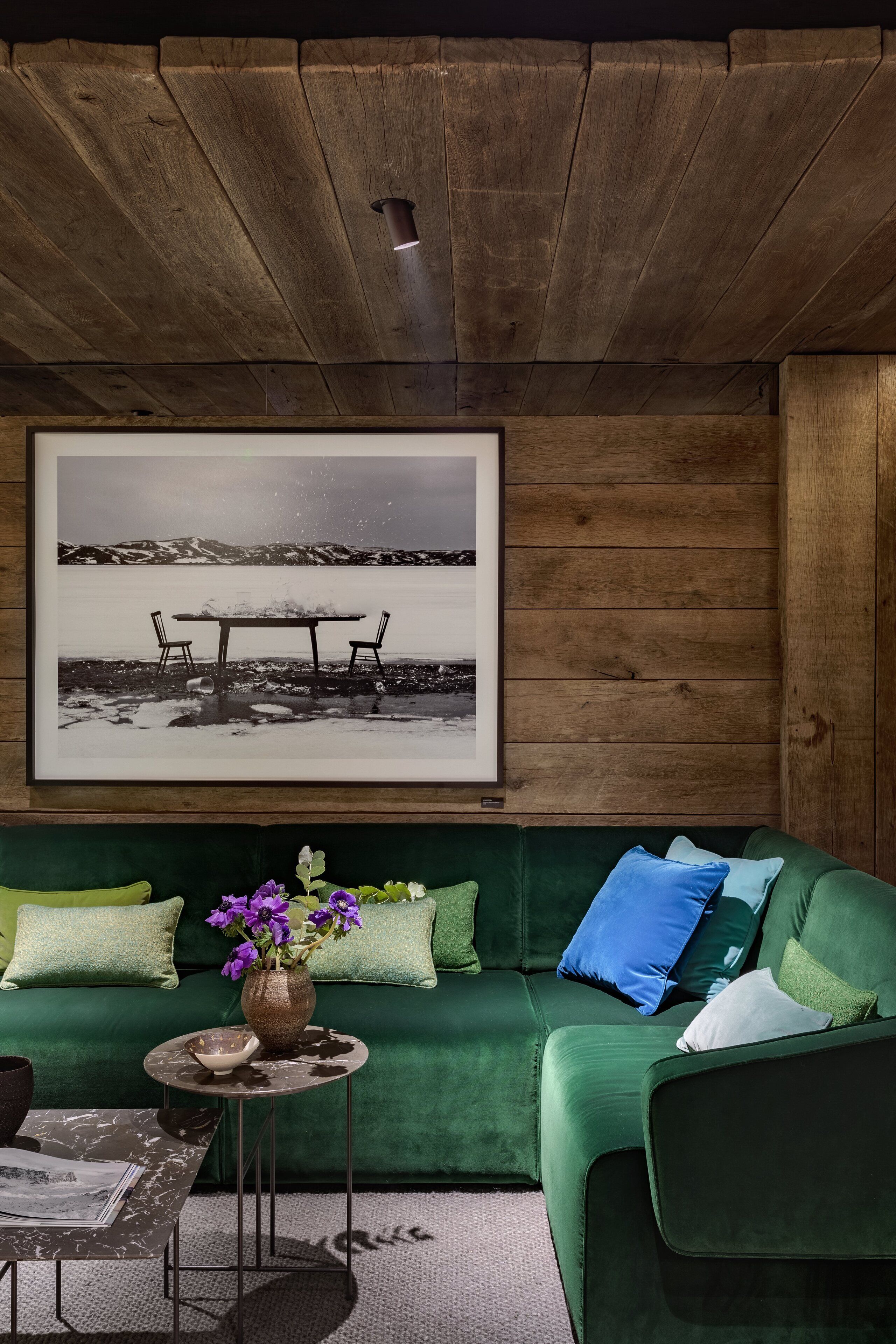 Una habitación acogedora con un sofá verde, una fotografía enmarcada en la pared y una mesita con un florero.
