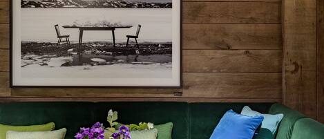 Una habitación acogedora con un sofá verde, una fotografía enmarcada en la pared y una mesita con un florero.