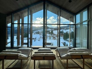 Una habitación con ventanas amplias que ofrecen vistas a un paisaje montañoso cubierto de nieve.