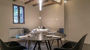 A conference room with a round table, black chairs, and a window with a view. - Antica Locanda Il Sole (Castel Maggiore)