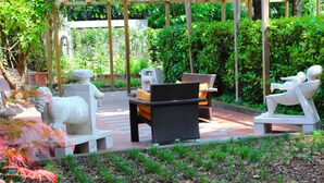 An outdoor seating area with stone sculptures, wicker furniture, and a pergola structure. - Antica Locanda Il Sole (Castel Maggiore)