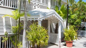 A two-story building with a white exterior, multiple balconies, and potted plants. - Amaudo (Saint-François)